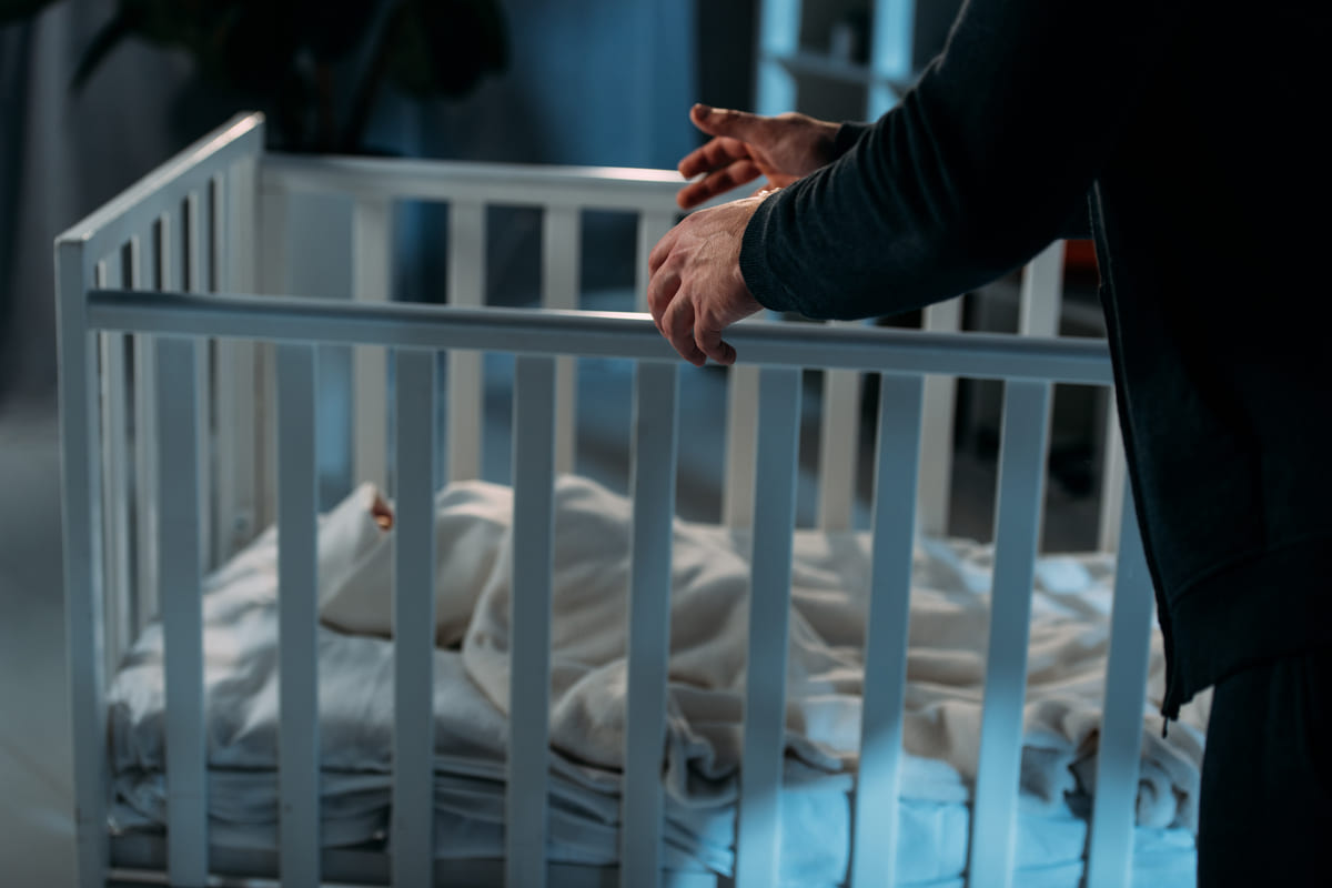 uomo vicino a un neonato in culla