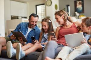 Una famiglia sul divano con telefoni e ipad