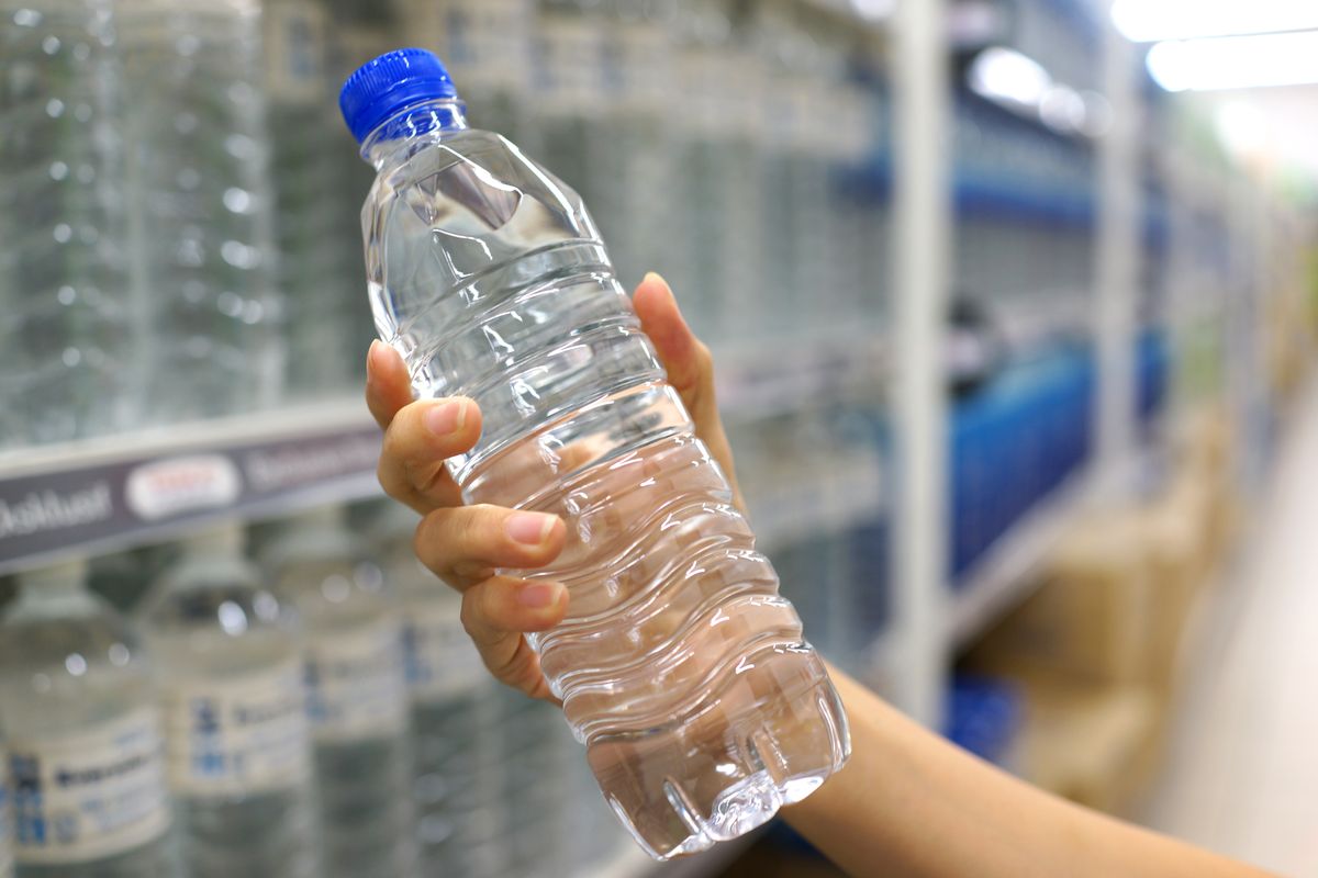 Persona che tiene in mano una bottiglia d'acqua di plastica