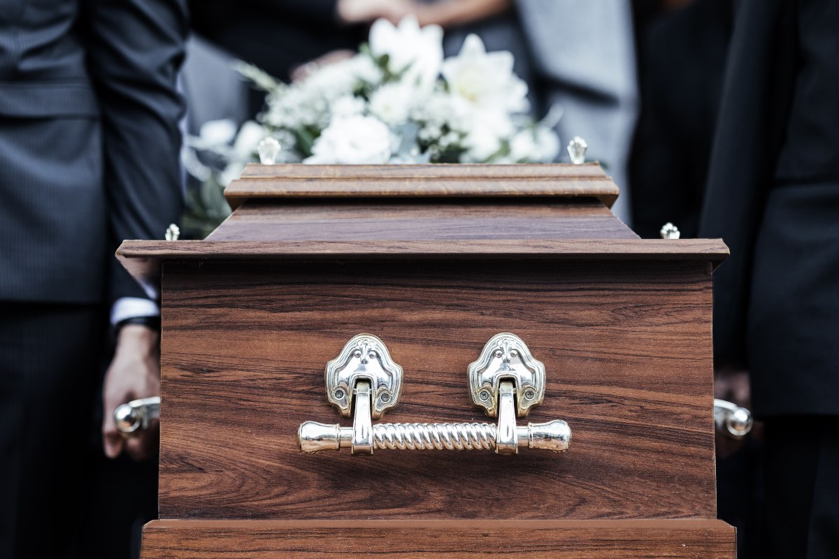 Cerimonia funebre con bara e fiori bianchi