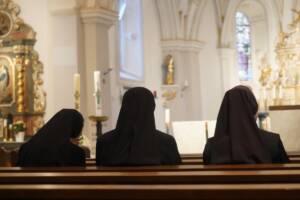 tre suore sedute all'interno di una chiesa