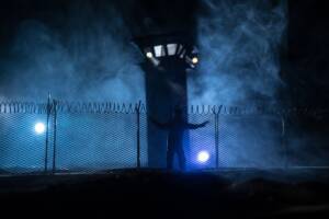 Sagoma d'uomo all'esterno di una prigione di notte durante una fuga.