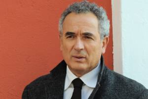 primo piano di Lamberto Sposini con una giacca scura e una cravatta
