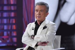 il cantante Pupo con volto serio e una giacca bianca